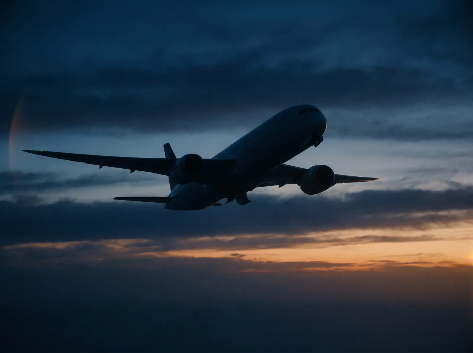 A commercial jet in dramatic silhouette against a sweeping twilight sky