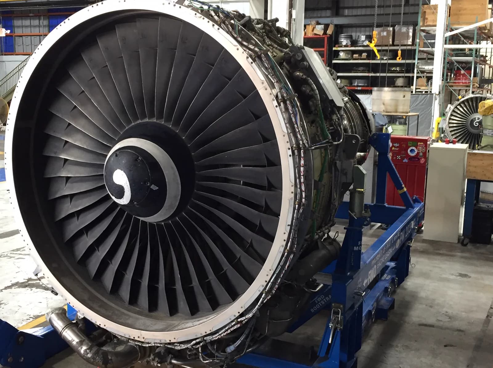 A commercial turbofan engine on a maintenance stand under dramatic light in a dark hangar